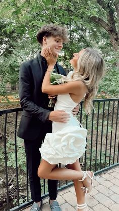 a man in a tuxedo is hugging a woman's face on the balcony