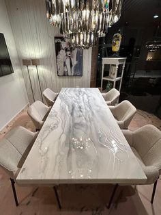 a marble dining table surrounded by chairs in a room with chandelier hanging from the ceiling