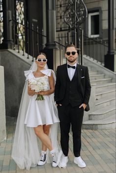 a man and woman in wedding attire standing next to each other on the steps outside