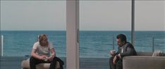 two people sitting on couches in front of the ocean