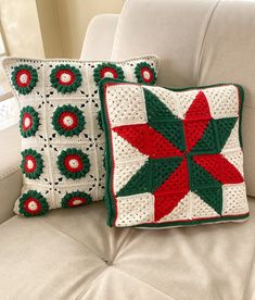 two crocheted pillows sitting on top of a white couch next to each other