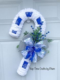 a christmas wreath with blue and white decorations hanging on the front door to give as a decoration