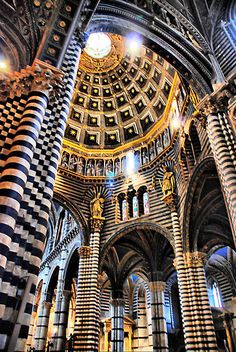 the inside of a building with many columns and arches, all decorated in black and white checkerboard