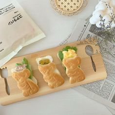 three small sandwiches are sitting on a cutting board next to some flowers and a napkin