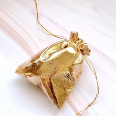 a gold colored bag with a bow on the front and side, sitting on a white surface