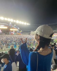 a woman wearing a face mask standing in front of an audience at a baseball game