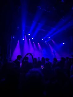 people are standing in front of purple and blue lights as they perform on the stage