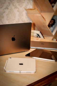 an apple laptop computer sitting on top of a wooden desk next to a macbook pro