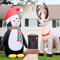 two large inflatable christmas reindeer and penguin standing next to each other on the lawn