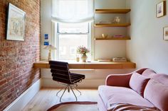 a living room with brick walls and a pink couch in front of a large window