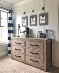 a dresser with drawers and pictures hanging on the wall in front of a striped curtain