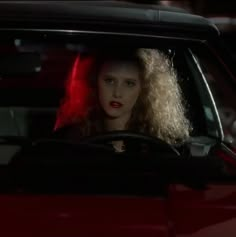 a woman with blonde hair sitting in a red car