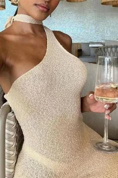 a woman holding a glass of wine in her right hand and wearing a halter top