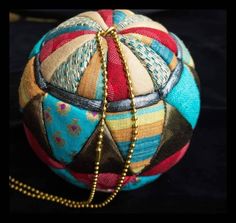 a multicolored patchwork ball with gold chains