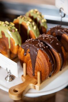 several pastries with chocolate and green toppings on a plate