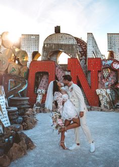 a newly married couple kissing in front of neon signs