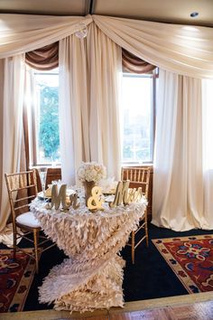 the table is decorated with white flowers and gold letters, along with other decor items