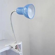 a blue light sitting on top of a white shelf next to a wall mounted lamp