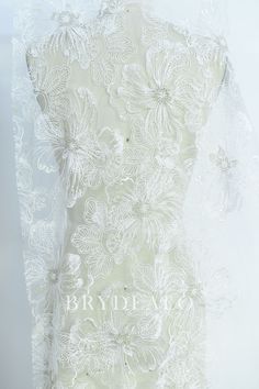 the back of a wedding dress with white flowers on it and lace overlays