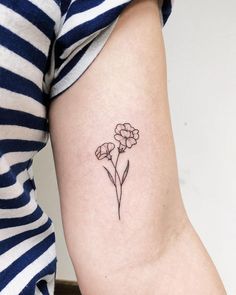 a small flower tattoo on the left inner arm and lower arm, is shown in black ink