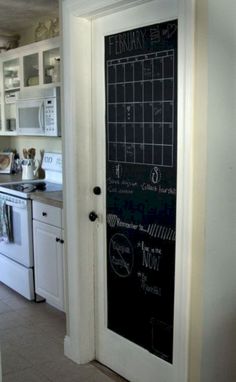 a chalkboard door is open to reveal the kitchen's white cabinets and appliances