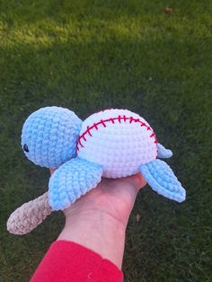 a hand holding a crocheted stuffed animal in the shape of a baseball bat