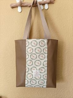 a brown and white tote bag hanging from a hook on a wall with two birds perched on it