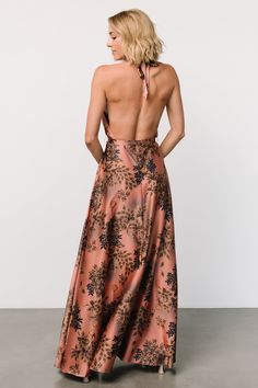 the back of a woman wearing a pink and black floral print dress with halter neck