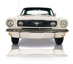 the front end of a white mustang car with its hood up and lights on, against a white background