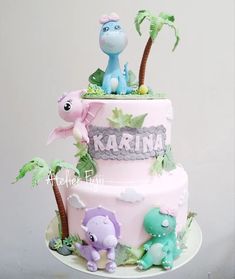 a three tiered cake decorated with animals and palm trees for a baby's first birthday