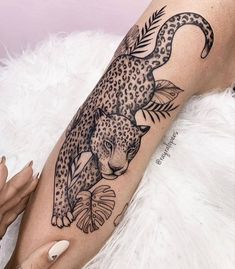 a woman's leg with a leopard and fish tattoo on her arm, next to a white fur rug