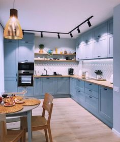 a kitchen with light blue cabinets and wooden chairs in front of the counter top area