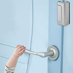 a small child's hand is holding onto the handle of a door lock on a blue wall