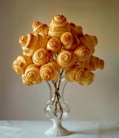 a glass vase filled with lots of doughnuts on top of a white table