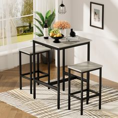 a kitchen table with three stools and a bowl of fruit on the counter top