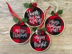 three plaid christmas ornaments hanging on a wooden surface with pine cones and holly berries in the center