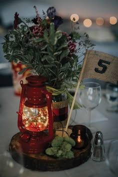 a red lantern is on top of a table with flowers and other items around it