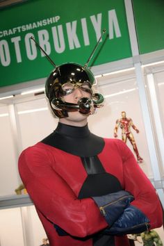 a man in a red and black costume with his arms crossed, wearing a helmet