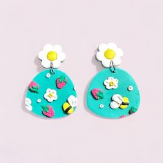 two pairs of earrings with flowers and fruit painted on the front, one is blue