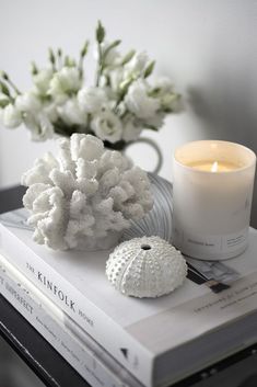 a candle and some white flowers on top of a book