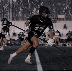 a lacrosse player is running with the ball in his hand and another player behind him