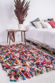 a large pile of scarves is on the floor next to a bed and table