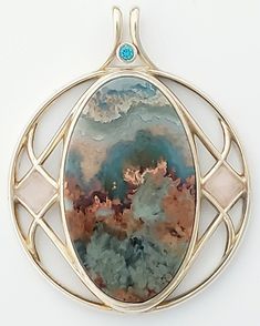 One of a kind, designer pendent with selected gemstones for their uniqueness, color, and metaphysical traits emphasizing health and well being in non-tarnishing Continuum Silver, Prudent Maw Plume Agate, Peach Moonstone cabs, 3mm. Blue Zircon faceted accent. Unique Moonstone Jewelry With Gemstone Accents, Artisan Jewelry With Oval Gemstone Accents, Artisan Agate Jewelry With Gemstone Accents, Artisan Oval Jewelry With Gemstone Accents, Fusion Style Oval Natural Gemstones, Artistic Gemstone Jewelry For Healing, Spiritual Oval Jewelry With Gemstone Accents, Oval Natural Stones Fusion Gemstones, Agate Gemstones With Gemstone Accents For Gifts