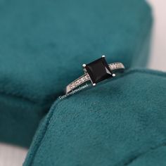 a black diamond ring sitting on top of a blue velvet cushion