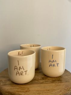 three white bowls with writing on them sitting on a wooden table