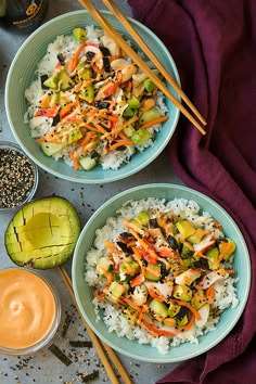 two blue bowls filled with rice and vegetables next to chopsticks on a table