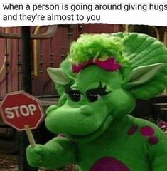 a green stuffed animal holding a stop sign