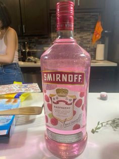 a bottle of smirnoff sitting on top of a counter next to a woman