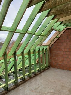 an attic with green wooden beams and brick wall in the foreground, under construction