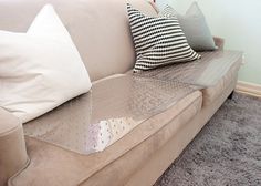 a couch with several pillows on it in front of a wall and carpeted floor